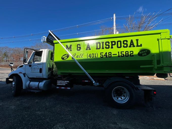 Bright green MGA Disposal truck parked on asphalt with blue sky background