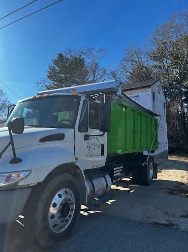 White truck with green dumpster parked on residential street